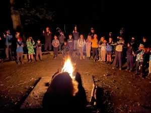 Young people gathered around a camp fire at night 